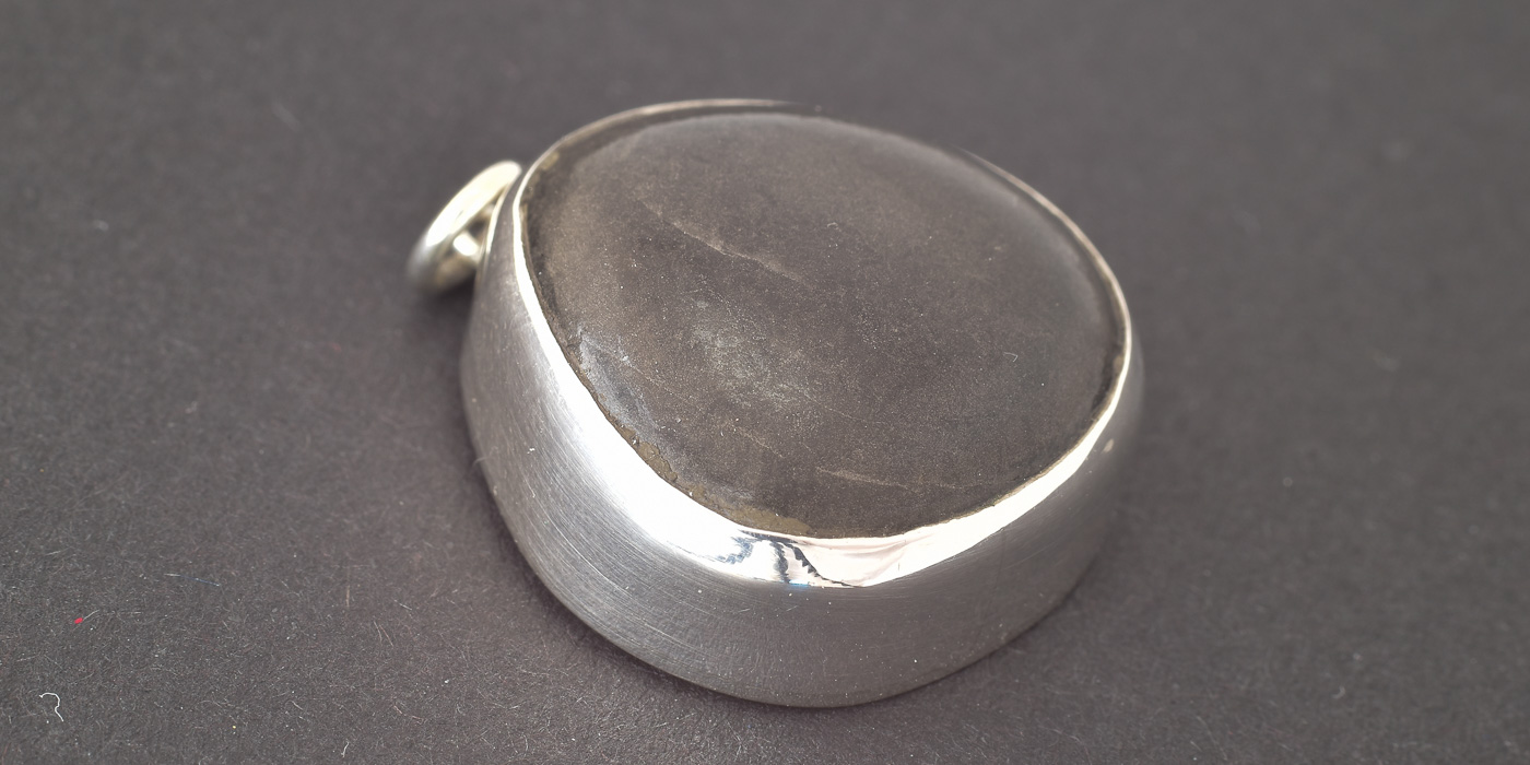 Handgefertigter Kiesel-Anhänger „Flüstern der Wellen“ – schwarzer Strandkiesel mit 925er Sterlingsilberfassung, maritimer Schmuck