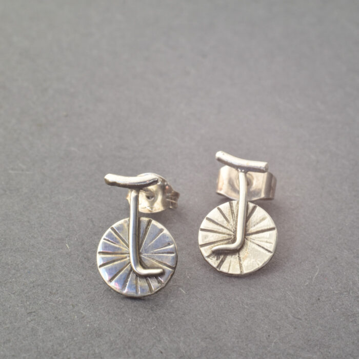 Silberne Einrad-Ohrstecker inspiriert von der Kunst des Ausbalancierens.