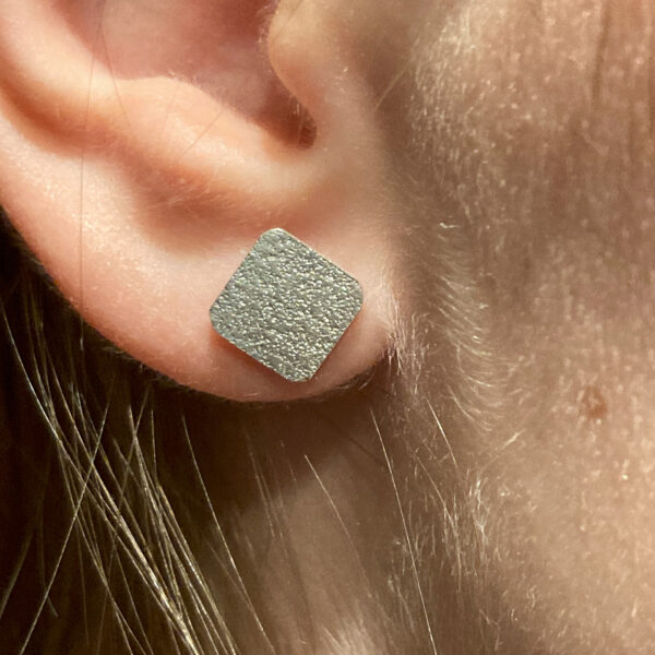 Paar Ohrstecker Wüstenwind aus recyceltem Silber mit sandiger Oberfläche getragen diagonal