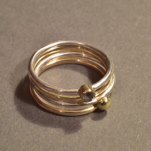 Vier handgefertigte Stackingringe aus Gold, Silber und Zirkonia – kombiniert getragen, inspiriert von Licht und Meer