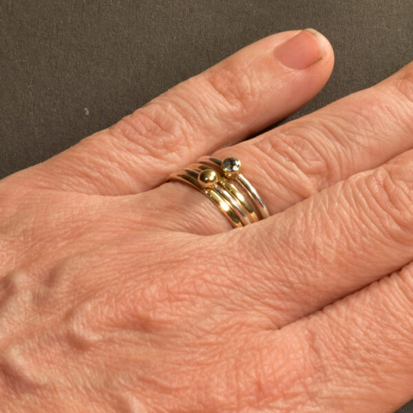 Vier Stackingringe aus Gold, Silber und Zirkonia an der Hand getragen – filigraner, maritimer Schmuckstil